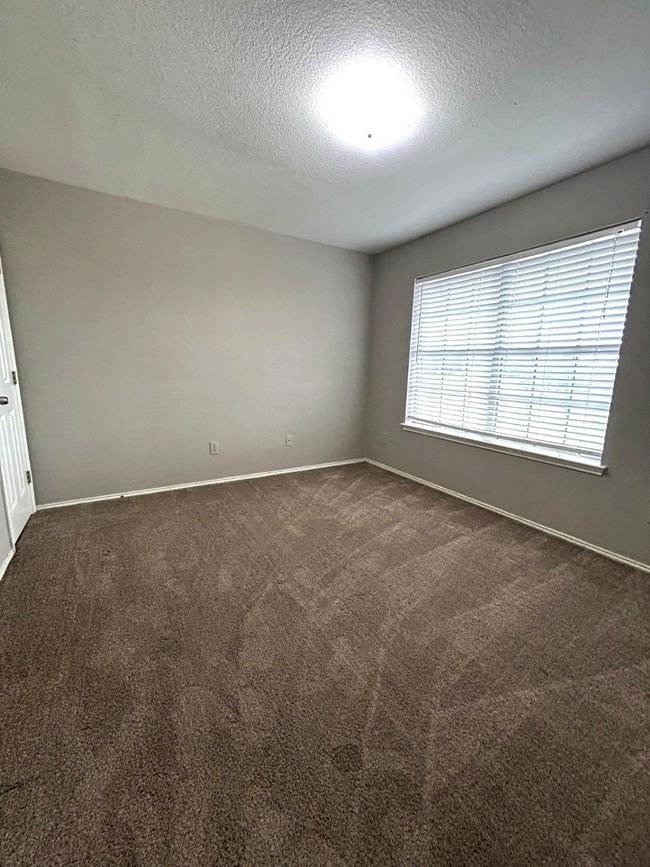 Spare room featuring a textured ceiling and dark colored carpet | Image 13