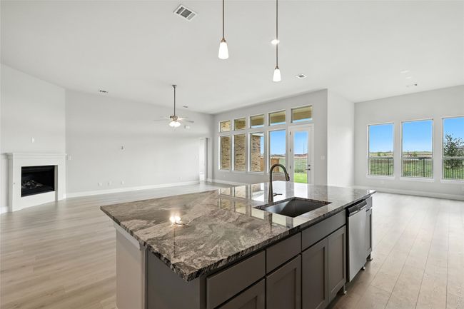 Kitchen with open floor plan, light wood-style floors, an island with sink, and stainless steel dishwasher | Image 5