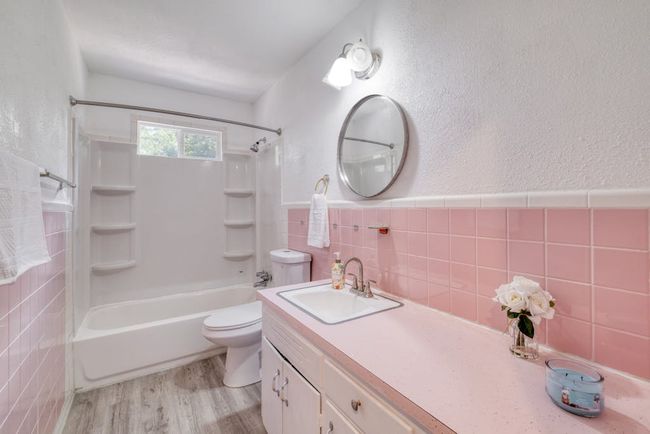 Full bathroom featuring 2024 toilet, 2018 shower / bath combination, 2024 laminate flooring, vanity, and original tile walls. | Image 20
