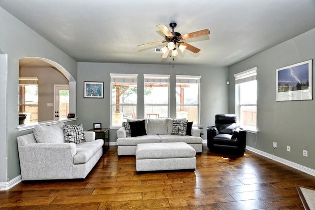 Living area featuring dark wood-style flooring, a ceiling fan, arched walkways, and baseboards | Image 6
