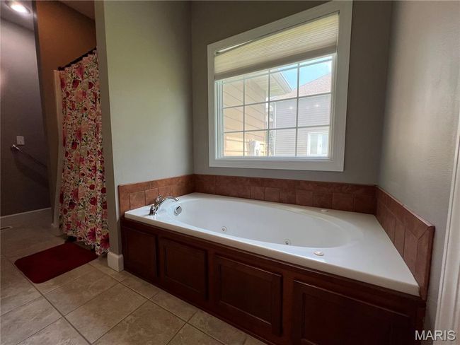 Bathroom with tile patterned floors, a whirlpool tub, and curtained shower | Image 13