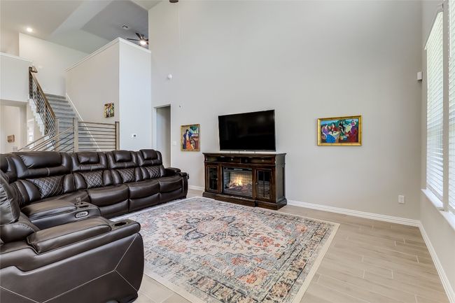 Living room featuring a towering ceiling, baseboards, light wood-style floors, stairway, and ceiling fan | Image 9