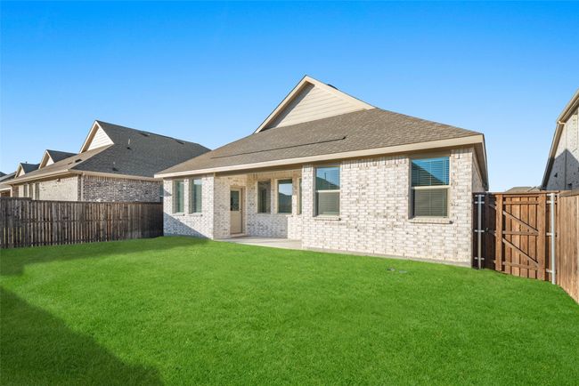 Rear view of property featuring a gate, brick siding, a shingled roof, and a patio area | Image 22