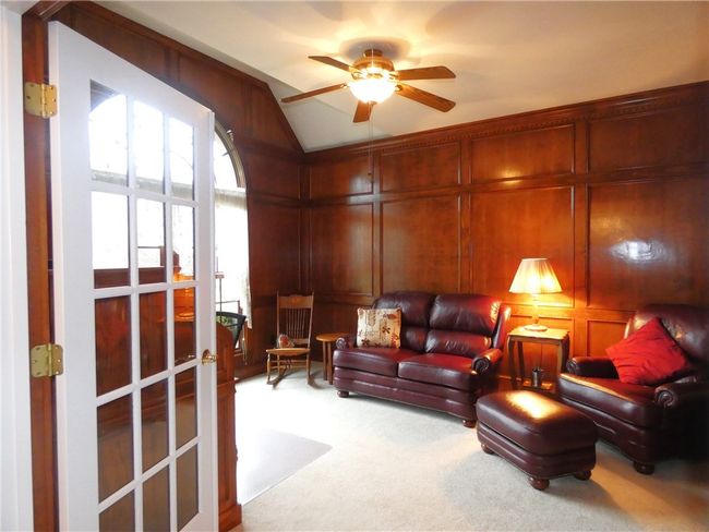 The den features paneled walls high ceiling and ceiling fan | Image 12