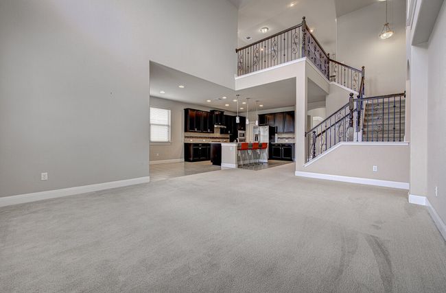 Unfurnished living room with a high ceiling, light carpet, stairs, and recessed lighting | Image 12