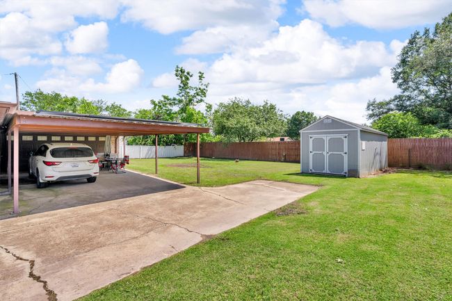 Car port that leads to double garage with large storage building. | Image 30