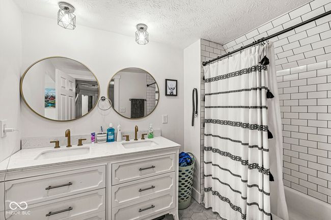 bathroom with double vanity, shower / bath combo, and a textured ceiling | Image 21