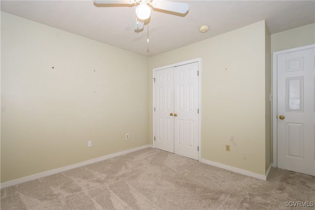 Unfurnished bedroom featuring light carpet, a closet, and a ceiling fan | Image 16