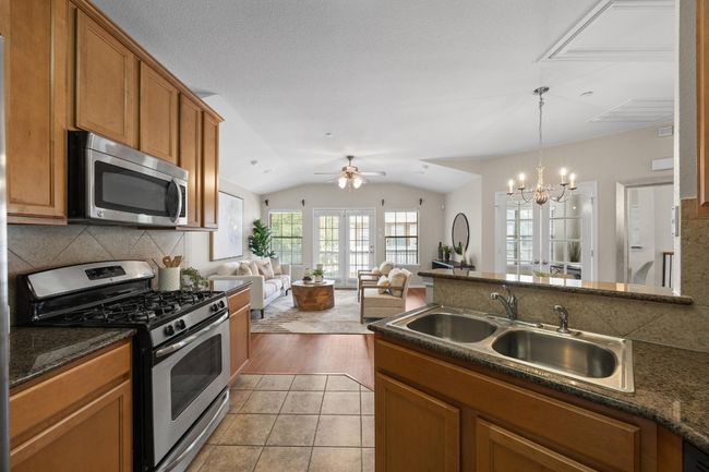 Kitchen featuring stainless steel appliances, brown cabinets, tile backsplash, and open floor plan | Image 15