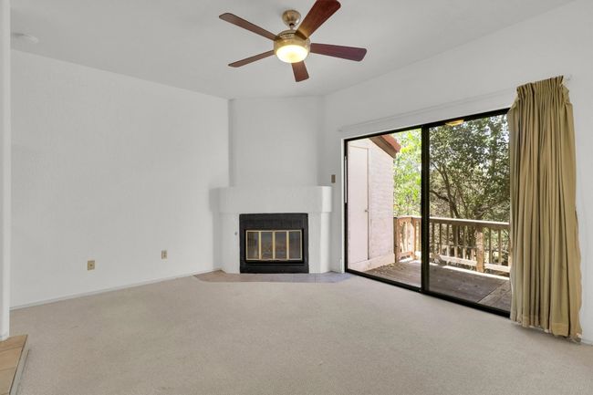 Unfurnished living room with a fireplace with flush hearth, carpet, and ceiling fan | Image 13