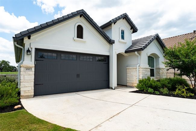 View of front of house with stone siding, a garage, driveway, a tiled roof, and stucco siding | Image 4
