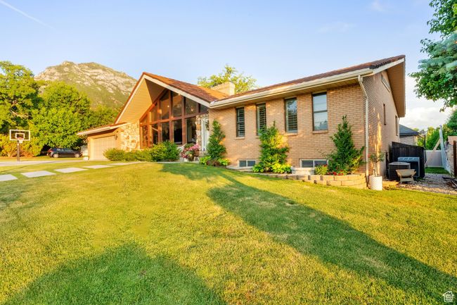 View of front of home featuring brick siding, concrete driveway, an attached garage, a mountain view, and a chimney | Image 41