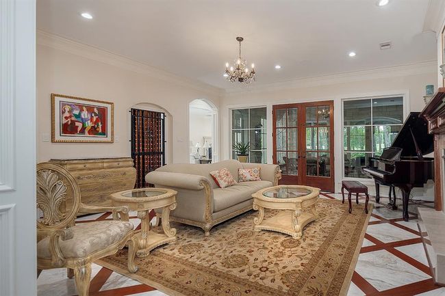 The formal living has a gated wine grotto, fireplace and doors that lead to a screened-in sunroom | Image 10