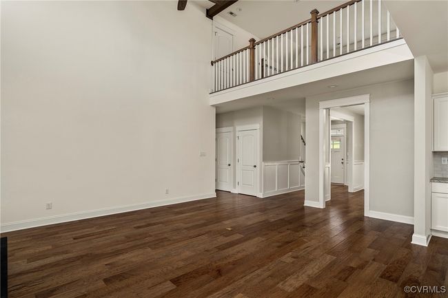 Unfurnished living room with dark wood finished floors and a towering ceiling | Image 9