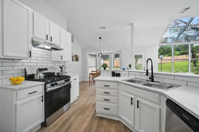 Kitchen with stainless steel appliances, under cabinet range hood, a sink, backsplash, and plenty of natural light | Image 10