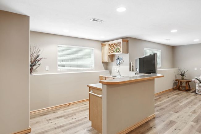 Kitchen featuring light wood finished floors, recessed lighting, baseboards, a peninsula, and light countertops | Image 19