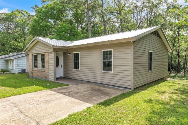 Single story home with a patio, a front lawn, and metal roof | Image 6