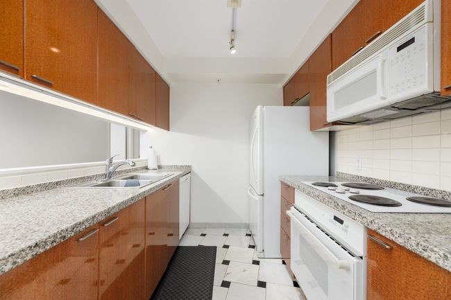 Kitchen featuring white appliances, brown cabinetry, a sink, light countertops, and tasteful backsplash | Image 4