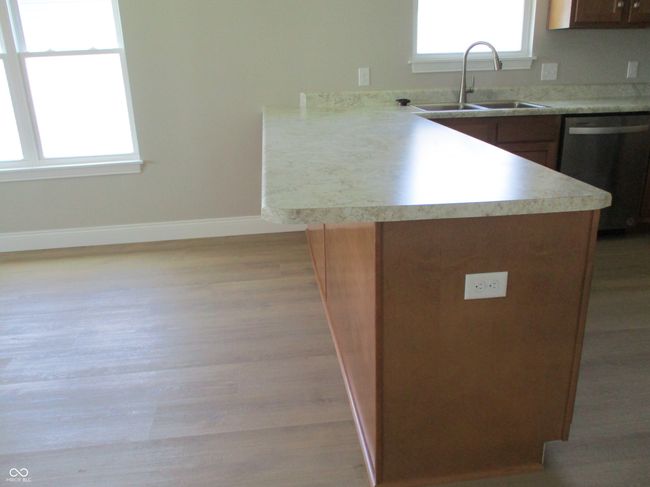 kitchen featuring light wood-style floors, a peninsula, light countertops, baseboards, and dishwasher | Image 9
