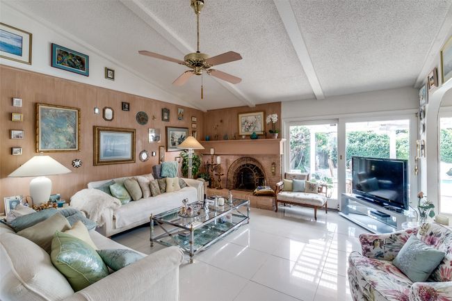 Living room featuring a textured ceiling, healthy amount of natural light, ceiling fan, a brick fireplace, and tile patterned floors | Image 6