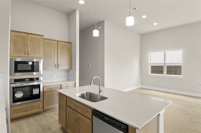 Kitchen with appliances with stainless steel finishes, a sink, light wood-type flooring, decorative backsplash, and pendant lighting | Image 20