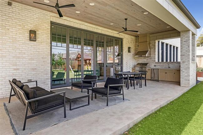 Expansive sliding glass doors seamlessly connect the indoors to the summer outdoor kitchen, featuring an Artisan grilling station, a prep sink, and custom cabinetry. This well-appointed space creates the perfect setting for effortless entertaining. | Image 8