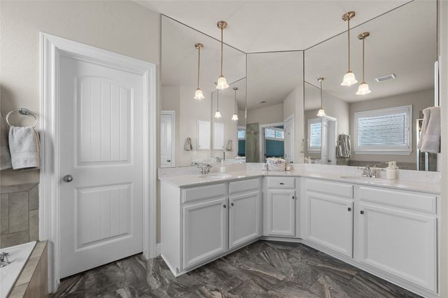 Primary Bathroom featuring double vanity, marble finish floors, and shower/tub. | Image 23
