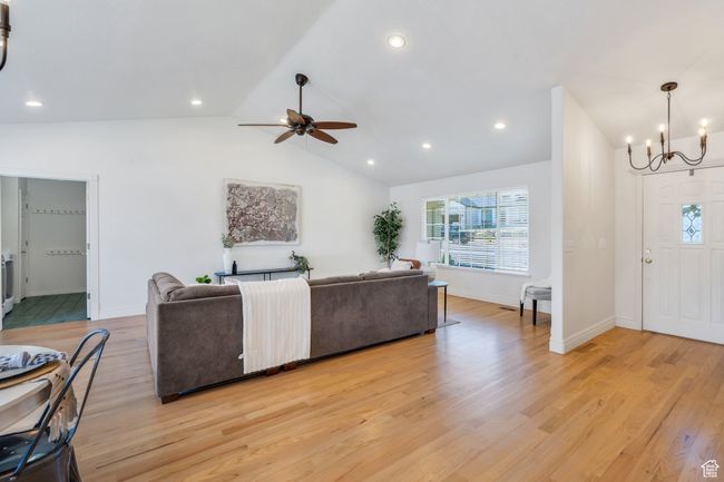 Living room with healthy amount of natural light, a chandelier, lofted ceiling, light wood-type flooring, and ceiling fan | Image 7