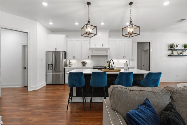 Kitchen featuring stainless steel fridge with ice dispenser, open floor plan, light countertops, white cabinetry, and visible vents | Image 8