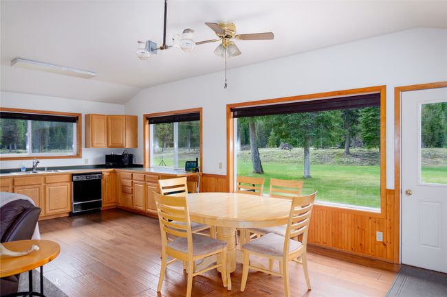 Dining space featuring lofted ceiling, light wood-style floors, wainscoting, wooden walls, and a ceiling fan | Image 88