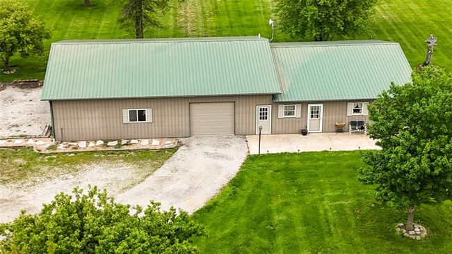 Side view of home with metal roof, driveway, an outbuilding, and a front yard | Image 12