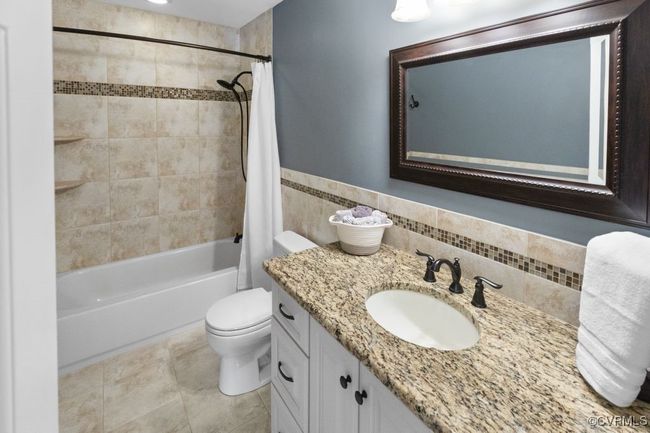 Full bathroom featuring shower / bath combo, toilet, vanity, tile walls, and tile patterned floors | Image 38