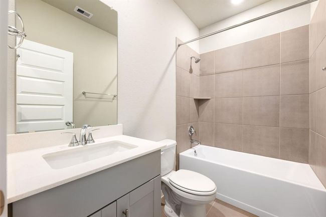 Secondary bathroom features Quartz countertops and cabinets, neutral paint, shower/tub combo with tile surround, large mirror, tile floors, sleek fixtures and modern finishes, plenty of space to accommodate any visiting family or guests. | Image 16