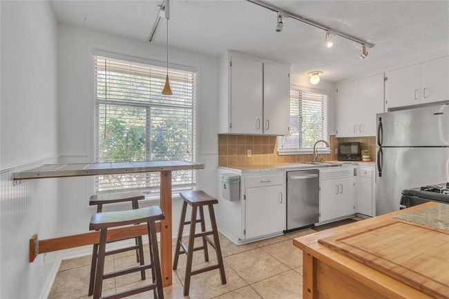 Kitchen with appliances with stainless steel finishes, decorative backsplash, track lighting, light countertops, and white cabinets | Image 6