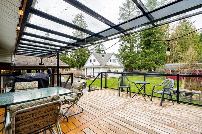 Wooden deck featuring a fenced backyard, outdoor dining space, and a yard | Image 4