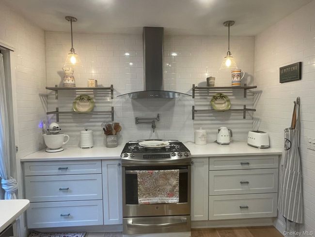 Bar featuring open shelves, gas range, wall chimney range hood, and tasteful backsplash | Image 4