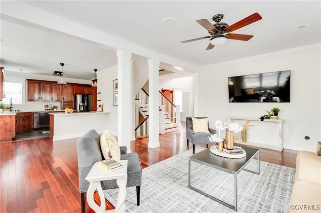 Living room with stairs, ceiling fan, ornamental molding, and dark wood-type flooring | Image 18