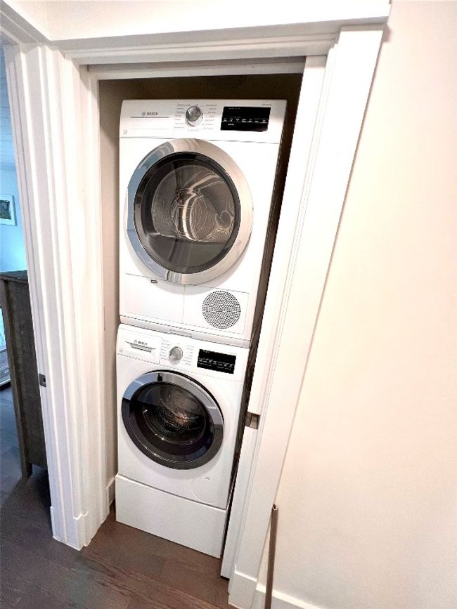 This photo shows a compact laundry area with a stacked Bosch washer and dryer set, neatly fitted into a closet space with sliding doors. | Image 9