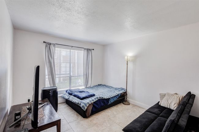Bedroom featuring light tile patterned floors, baseboards, and a textured ceiling | Image 4