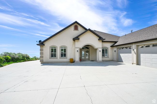 View of front of home with an attached garage, french doors, stucco siding, roof with shingles, and driveway | Image 4