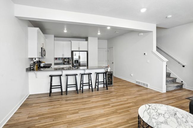 Kitchen featuring stainless steel refrigerator with ice dispenser, a peninsula, new light wood-style LVP floors, a breakfast bar area, and recessed lighting | Image 10