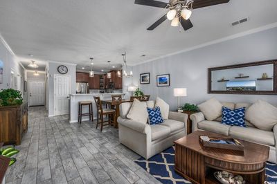 Living room with light hardwood / wood-style floors, crown molding, a textured ceiling, and ceiling fan with notable chandelier | Image 3