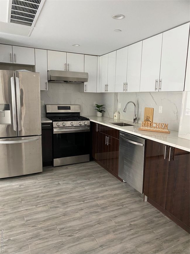 Kitchen with appliances with stainless steel finishes, white cabinets, tasteful backsplash, modern cabinets, and range hood | Image 6