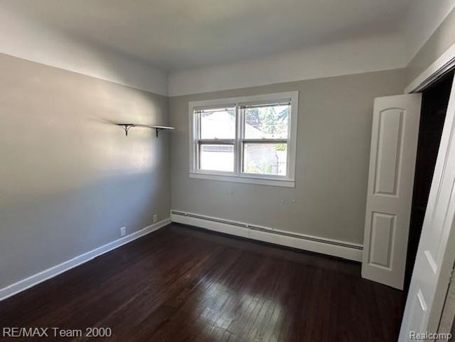 Unfurnished bedroom with dark wood-type flooring and baseboard heating | Image 14