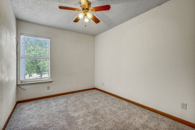 Carpeted empty room featuring a textured ceiling, ceiling fan, and baseboards | Image 12