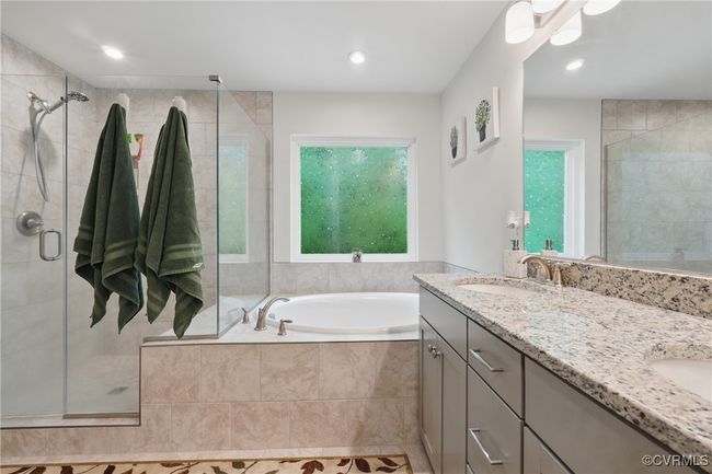 Spa-like ensuite bath with dual vanities, walk-in shower, and soaking tub. | Image 20