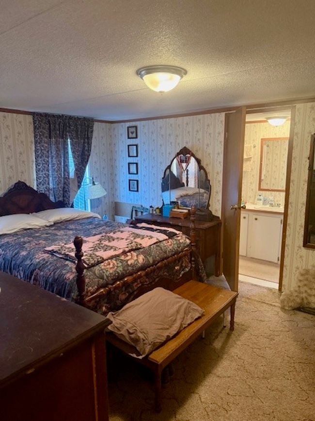 Carpeted bedroom featuring a textured ceiling, wallpapered walls, and ornamental molding | Image 22