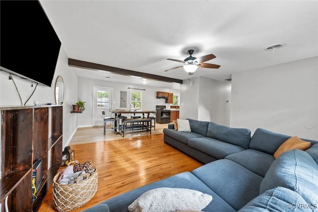Living room with beamed ceiling, ceiling fan, light wood-type flooring, visible vents, and baseboards | Image 8