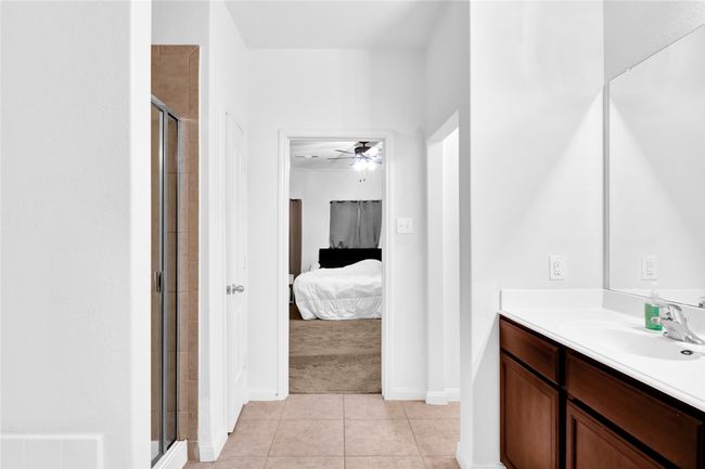 Bathroom featuring vanity, tile patterned floors, ensuite bath, a shower stall, and ceiling fan | Image 17