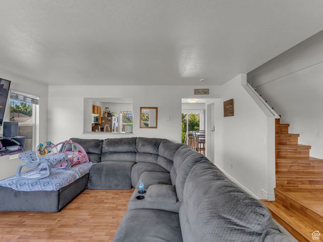 Living area with light wood-style floors, plenty of natural light, and stairway | Image 8
